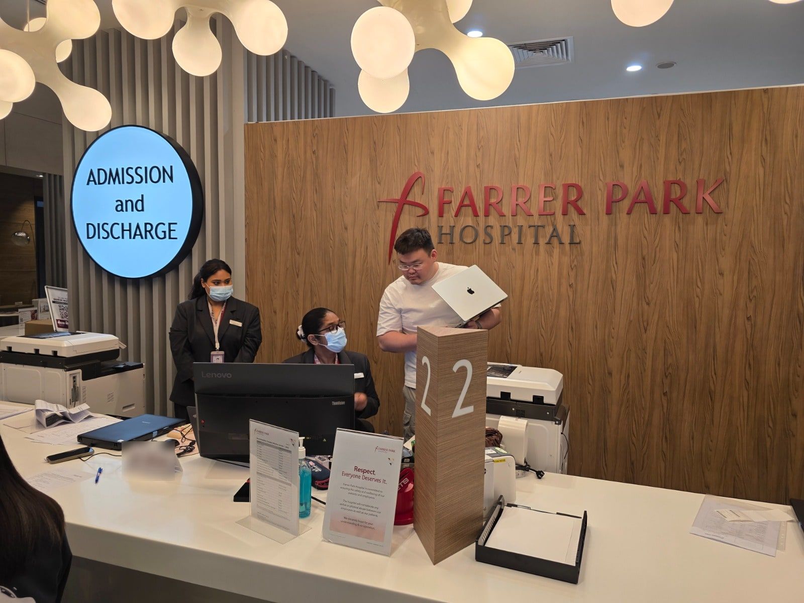 A Code Campus engineer working with admissions staff at Farrer Park Hospital.